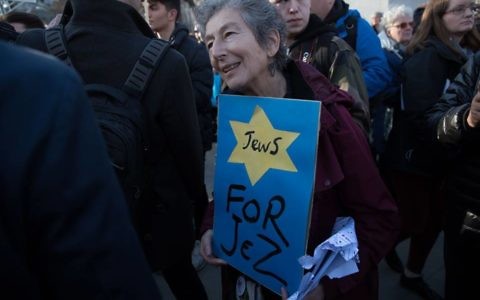 Naomi Wimborne-Idrissi, of Jewish Voice for Labour holds up a sign at the #EnoughIsEnough Demonstration against antixemitism, featuring a yellow star and the word Jews

Photo Credit: Marc Morris