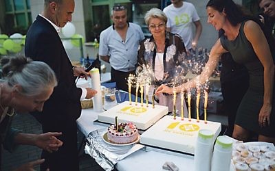 Members of the JCC celebrate its 10th anniversary with a cake and sparklers