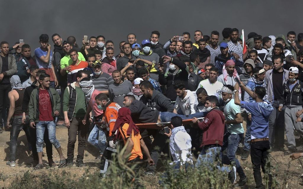 Palestinian protesters carry a wounded man from during a protest at the Gaza Strip's border with Israel, Friday, April 6, 2018. (AP Photo/ Khalil Hamra)