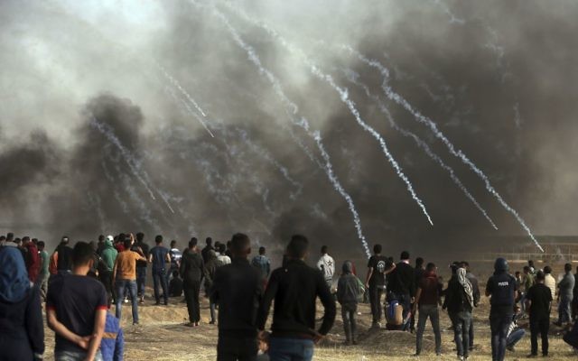 Israeli troops fire teargas at Palestinians during a protest at the Gaza Strip's border with Israel, Friday, April 13, 2018. (AP Photo/ Khalil Hamra)