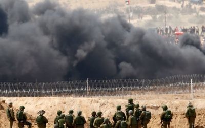 Israeli soldiers take position as Palestinians protest on the Israel Gaza Strip Border, Friday, April 13, 2018. (AP Photo/Ariel Schalit)