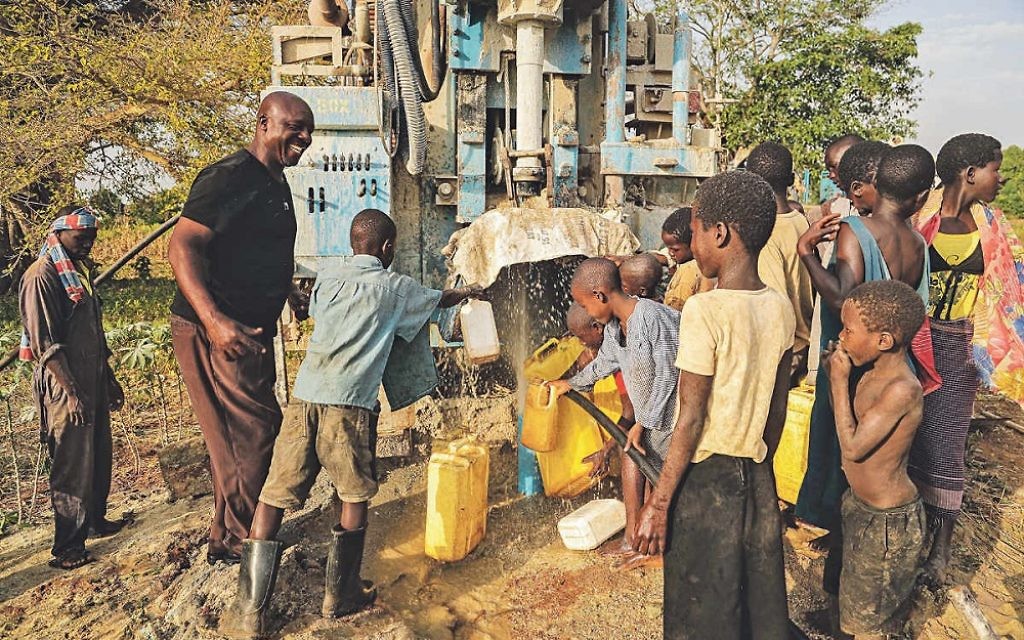 Villagers gather round their new water pumping system
