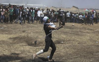 A Palestinian protester slings a stone towards Israeli troops during a protest at the Gaza Strip's border with Israel, Monday, May 14, 2018
. (AP Photo/Khalil Hamra)