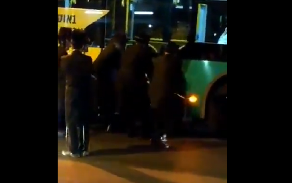 Screenshot from video of the incident, shows Charedi men ripping off a poster from a bus, showing their opposition to  Rachel Azaria's candidacy