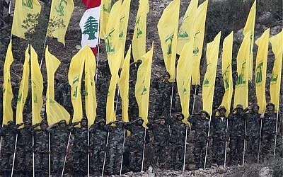 Hezbollah flags paraded at a rally, with one Lebanese flag