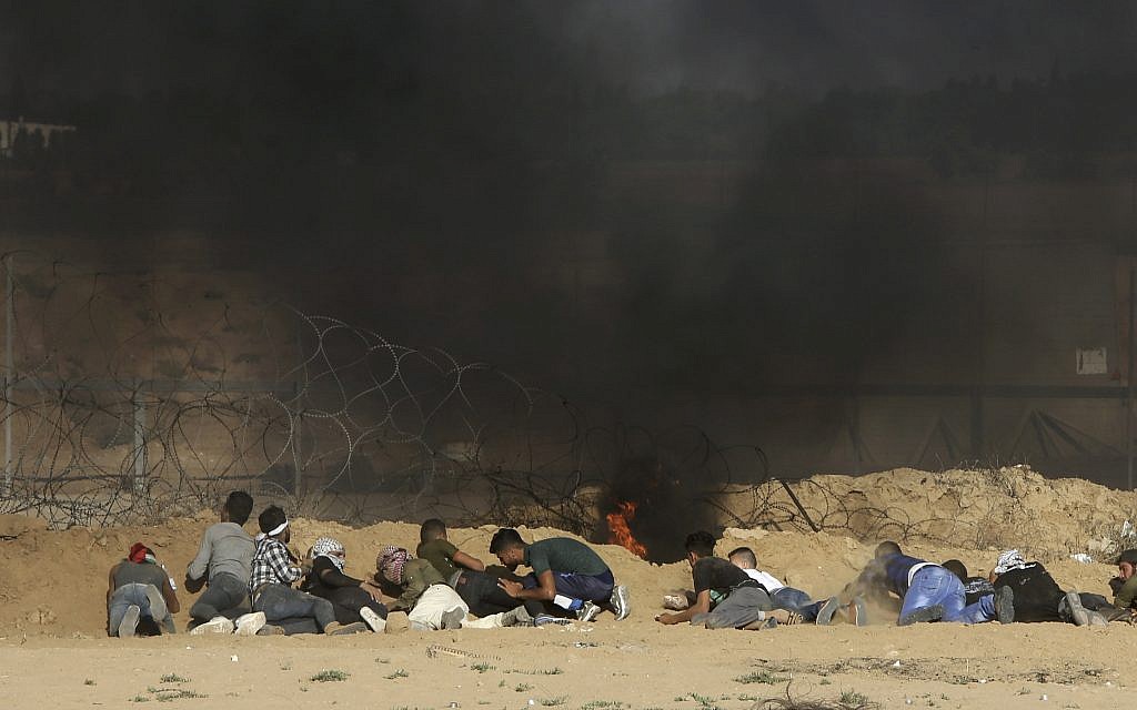 Protesters take cover from shooting and teargas fired by Israeli troops near the fence of the Gaza Strip border with Israel, during a protest east of Khan Younis, southern Gaza Strip, Friday, Aug. 17, 2018.    (AP Photo/Adel Hana)