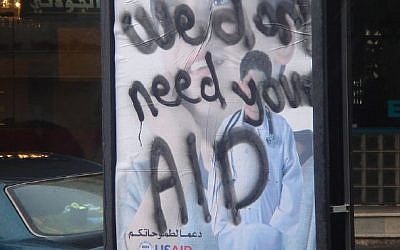 A poster in the West Bank from 2007 for USAID, daubed with graffiti on it saying "We don't need your AID"