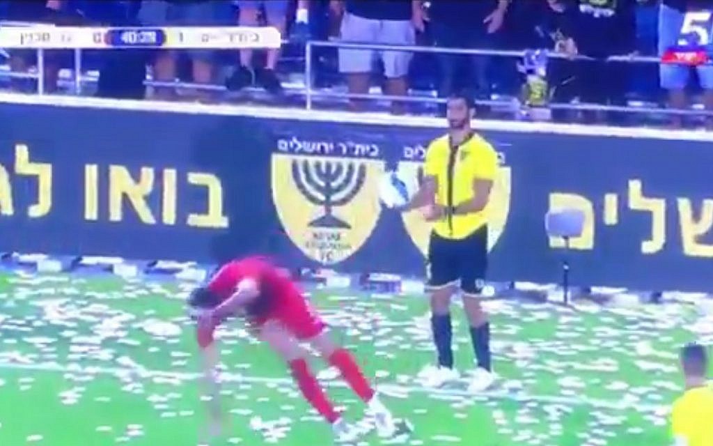 The Bnei Sakhnin player goes to ground, while Ofir Kriaf waits to take a throw in