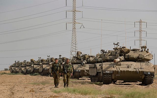 Israeli soldiers seen walking next to Merkava tanks t stationed in an open area near Israel's border with the Gaza Strip in October  2018. Photo by: JINIPIX