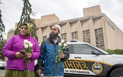 Samina Mohamedali, left, and her husband Kutub Ganiwalla, members of the Dawoodi Bohra Muslim community, both of North Hills, prepare to place flowers on a memorial in front of the Tree of Life Congregation, Sunday, Oct. 28, 2018, in Squirrel Hill neighborhood of Pittsburgh. (Alexandra Wimley/Pittsburgh Post-Gazette via AP)