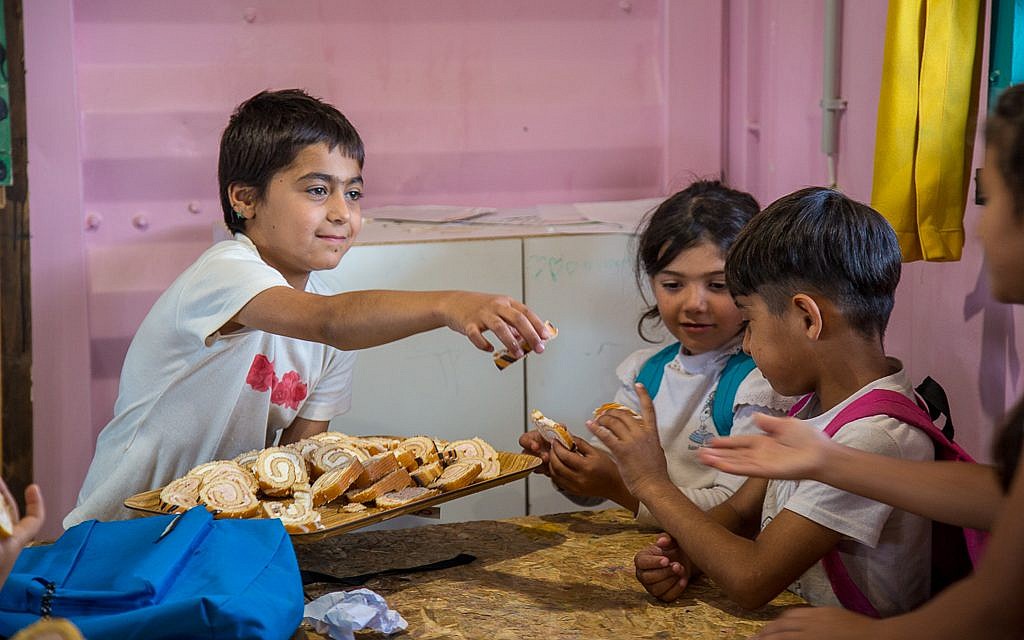 Children share treats in the School of Peace, Lesbos. Photo Credit - Lisa Kristine Children share treats in the School of Peace, Lesbos. Photo Credit - Lisa Kristine