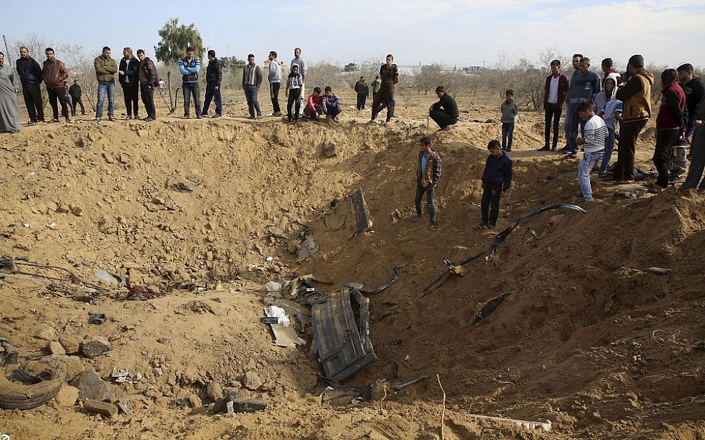 Palestinians inspect a crater and the wreckage of vehicles destroyed by an Israeli raid that killed seven Hamas Palestinian militants late Sunday, east of Khan Younis, southern Gaza Strip, Monday, Nov. 12, 2018. Chanting "revenge" and flanked by masked gunmen in camouflage, thousands of mourners in the Gaza Strip on Monday buried the seven who were killed in the Israeli incursion as the ruling Hamas group launched a feverish security sweep across the territory. (AP Photo/Adel Hana)