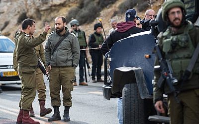 Israeli forces  inspect the site of a Palestinian drive-by shooting attack outside the West Bank settlement of Givat Asaf, northeast of Ramallah, on December 13, 2018. - Two Israelis were killed and at least two others were wounded at the bus stop in the West Bank Photo by: JINIPIX