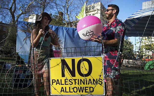 Two models stand on a "barbed-wire beach" outside the offices of TripAdvisor in Soho Square, as part of an Amnesty International campaign calling on the firm and other travel companies to stop listing rooms and activities in Israeli settlements in the Palestinian Territories.  Photo credit: Kirsty O'Connor/PA Wire
