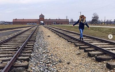 Picture posted by the Auschwitz Museum showing a visitor balancing on the tracks