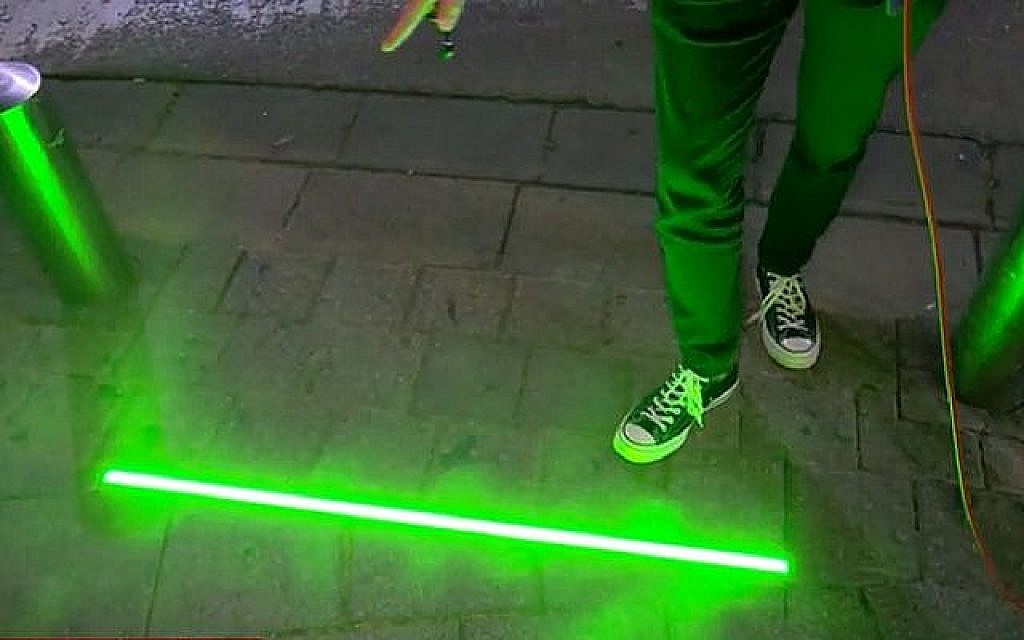 Tel Aviv testing new devices embedded in sidewalk to alert pedestrians when the stoplight has changed. (Screenshot, Channel 12 News via Times of Israel)