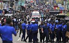 Sri Lankan police officers clear the road as an ambulance drives through carrying injured of Church blasts in Colombo, Sri Lanka, Sunday, April 21, 2019. A Sri Lanka hospital spokesman says several blasts on Easter Sunday have killed dozens of people. (AP Photo/Eranga Jayawardena)