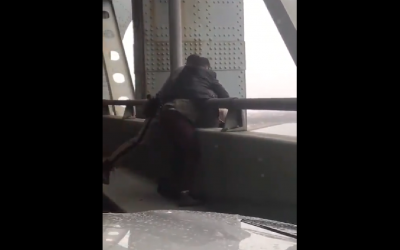 Screenshot from Twitter video showing Tuli Abraham, 30, help save someone's life on the bridge, alongside police officers