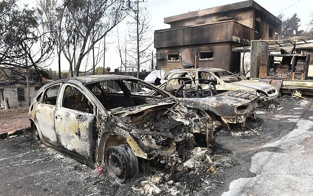 Charred cars and a damaged building are pictured in the village of Mevo Modi'im, in central Israel on May 24, 2019 following a fire amidst extreme heat wave. Photo by: JINIPIX