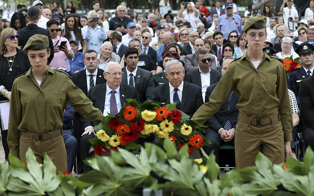 Israeli soldiers hold a wreath as Israeli Prime Minister Benjamin Netanyahu, center, Israeli President Reuven Rivlin, center left, and other guests attend the opening ceremony of Israel's annual Holocaust Remembrance Day, at Yad Vashem, the Holocaust Memorial, in Jerusalem, Thursday, May 2, 2019. The somber day is also marked by ceremonies and memorials at schools and community centers. Restaurants and cafes close, and TV and radio stations play quiet music and Holocaust-themed programs. (Abir Sultan/Pool Photo via AP)