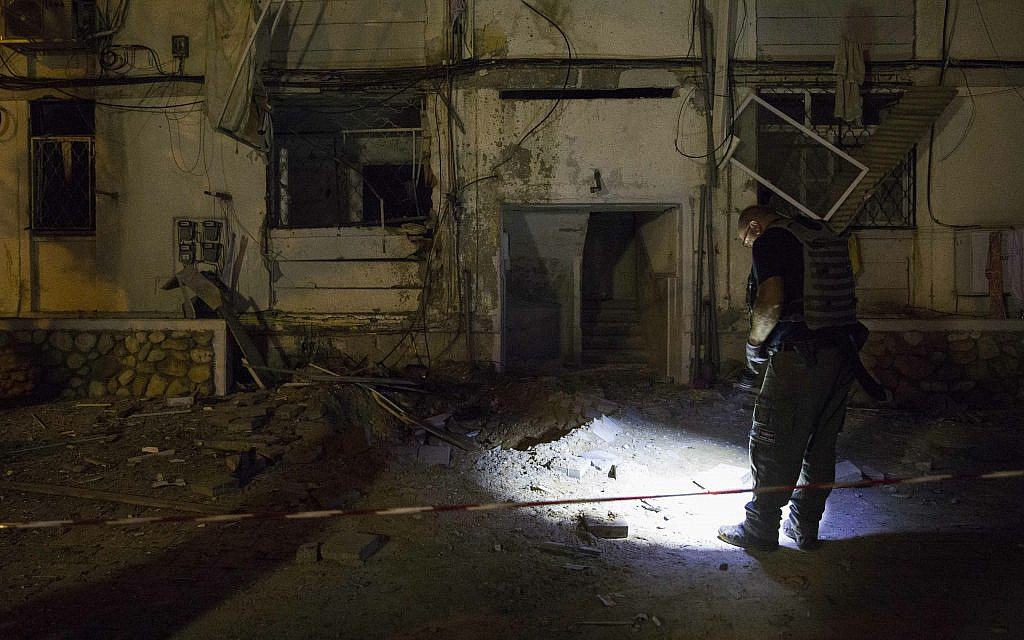 A policeman stands outside a residential building after it was hit by a rocket fired from Gaza in the costal city of Ashkelon, Israel, Sunday, May 5, 2019.  (AP Photo/Tsafrir Abayov)