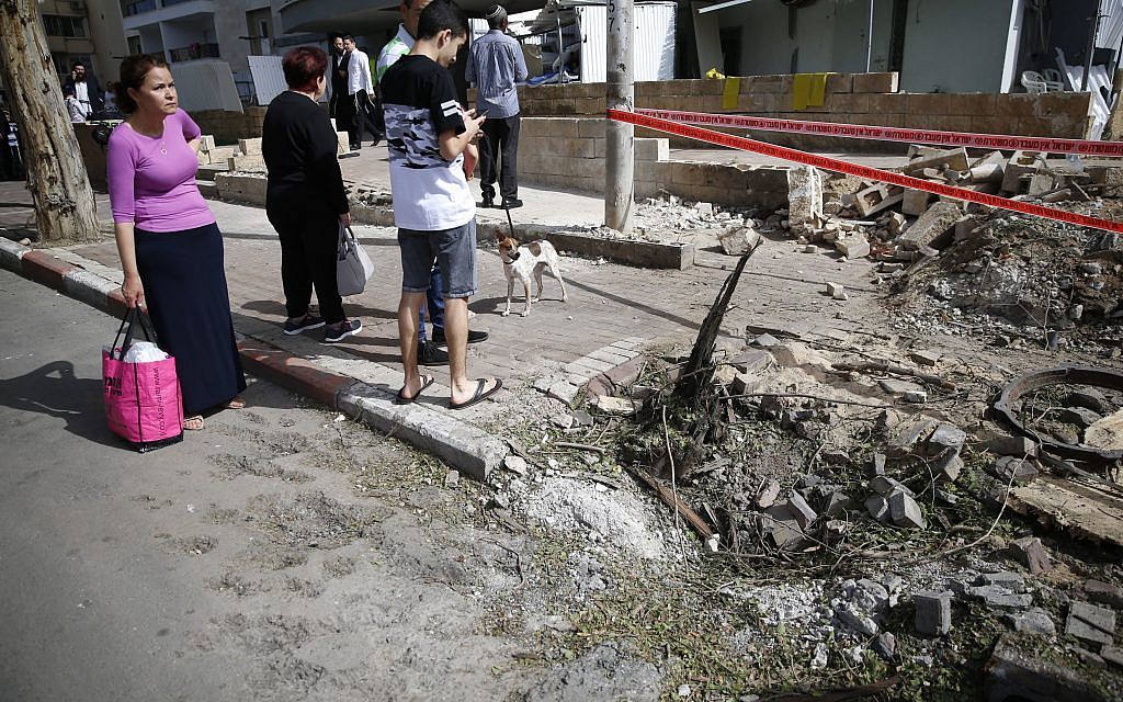People watch the aftermath of a rocket fired from Gaza after it hit in the southern Israeli port city of Ashdod, Monday, May 6, 2019.   (AP Photo/Ariel Schalit)