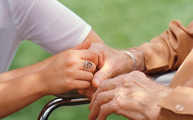 Nurse holding elderly person's hand