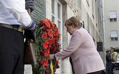 German Chancellor Angela Merkel adjusts a wreath during a memorial event at the Defence Ministry in Berlin, Germany, Saturday, July 20, 2019. On July 20, 2019 Germany marks the 75th anniversary of the failed attempt to kill Hitler in 1944. (AP Photo/Michael Sohn)