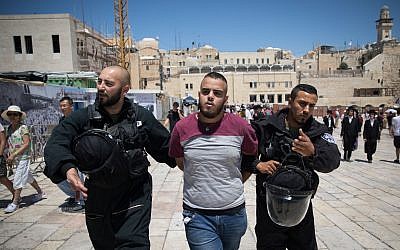 Israeli police with a detained Palestinian Muslim at the Western Wall Plaza in the Old City of Jerusalem after clashes broke out on the Temple Mount