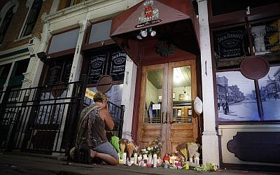 Mourners visit a makeshift memorial outside Ned Peppers bar following a vigil at the scene of a mass shooting, Sunday, Aug. 4, 2019, in Dayton, Ohio. A masked gunman in body armor opened fire early Sunday in the popular entertainment district in Dayton, killing several people, including his sister, and wounding dozens before he was quickly slain by police, officials said. (AP Photo/John Minchillo)