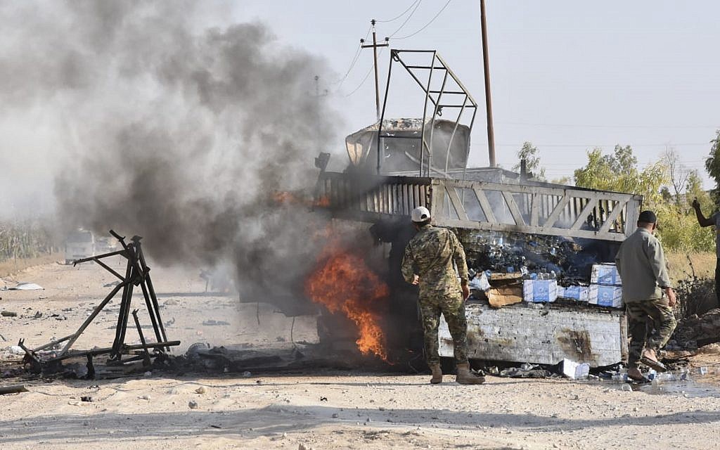 Popular Mobilization Forces members stand by a bruning truck after a drone attack near Qaim border crossing, in Anbar province, Iraq Sunday, Aug. 25, 2019.  (AP Photo)