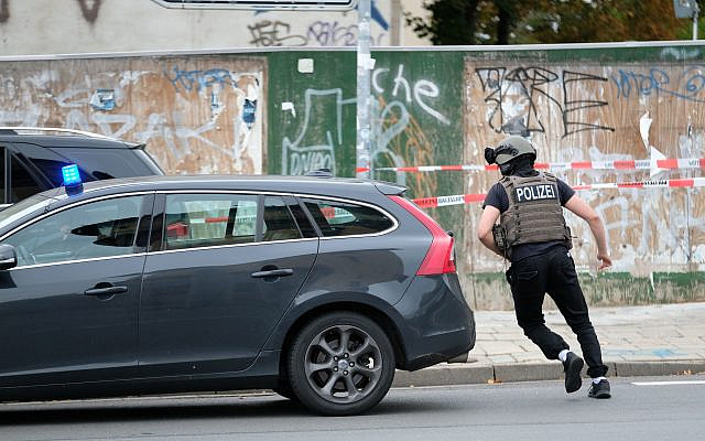 Police officer runs on a road in Halle, Germany, Wednesday, Oct. 9, 2019. (Sebastian Willnow/dpa via AP)
