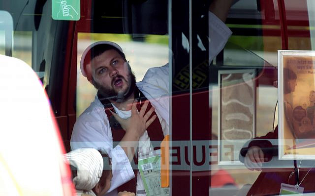 A man, wearing traditional Jewish clothing, reacts after he was escorted by the police to a bus at a Jewish cemetery and synagogue in Halle, Germany, Wednesday, Oct. 9, 2019. A heavily armed assailant tried to force his way into a synagogue Wednesday in eastern Germany on Yom Kippur, Judaism's holiest day, and two people were killed as he fired shots outside the building and into a kebab shop, authorities and witnesses said. (AP Photo Jens Meyer)