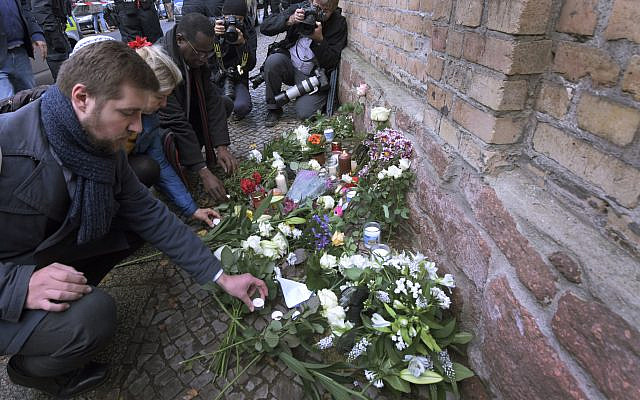 People place down flowers in front of a synagogue in Halle, Germany, Thursday, Oct. 10, 2019  (AP Photo/Jens Meyer)