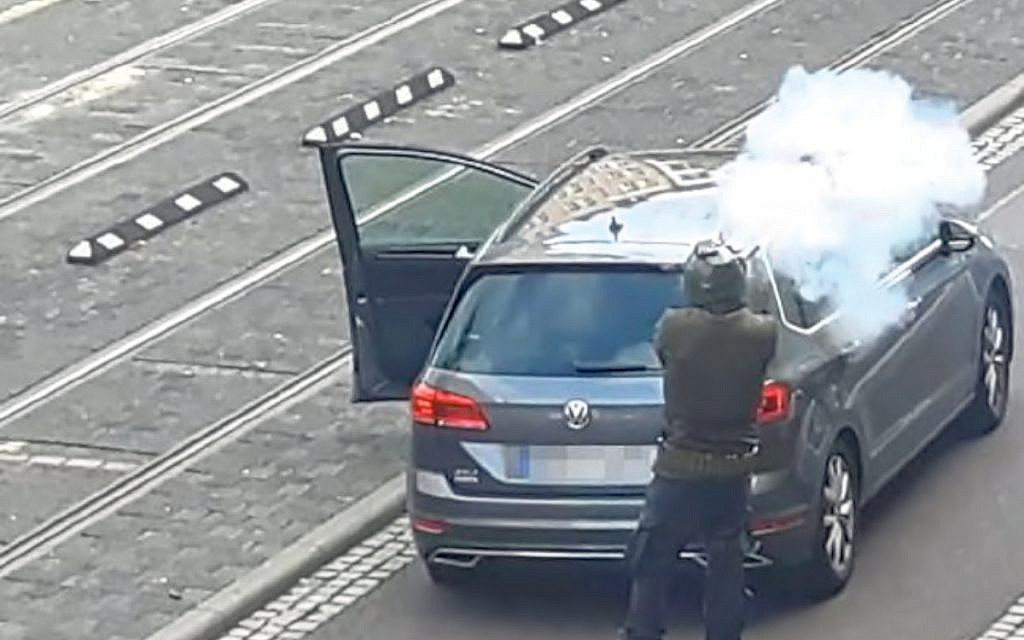 The suspect fires his weapon from behind his car