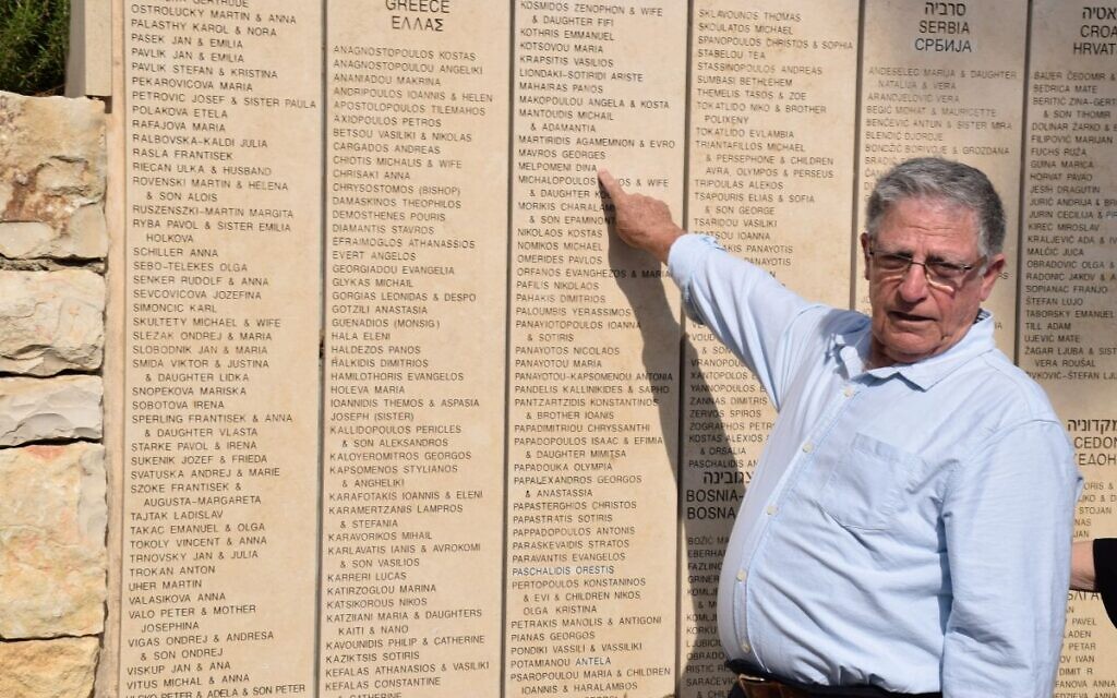 Yossi Mor pointing to Melpomeni Dina's name, inscribed on the Wall of Honor in the Garden of the Righteous Among the Nations at Yad Vashem
 (Credit: Yad Vashem)