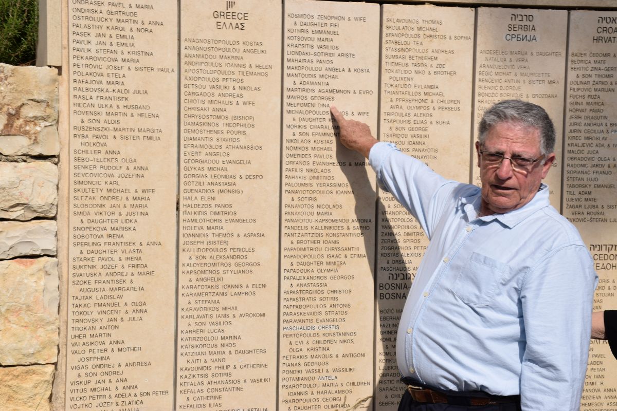 Yossi Mor pointing to Melpomeni Dina's name, inscribed on the Wall of Honor in the Garden of the Righteous Among the Nations at Yad Vashem
 (Credit: Yad Vashem)