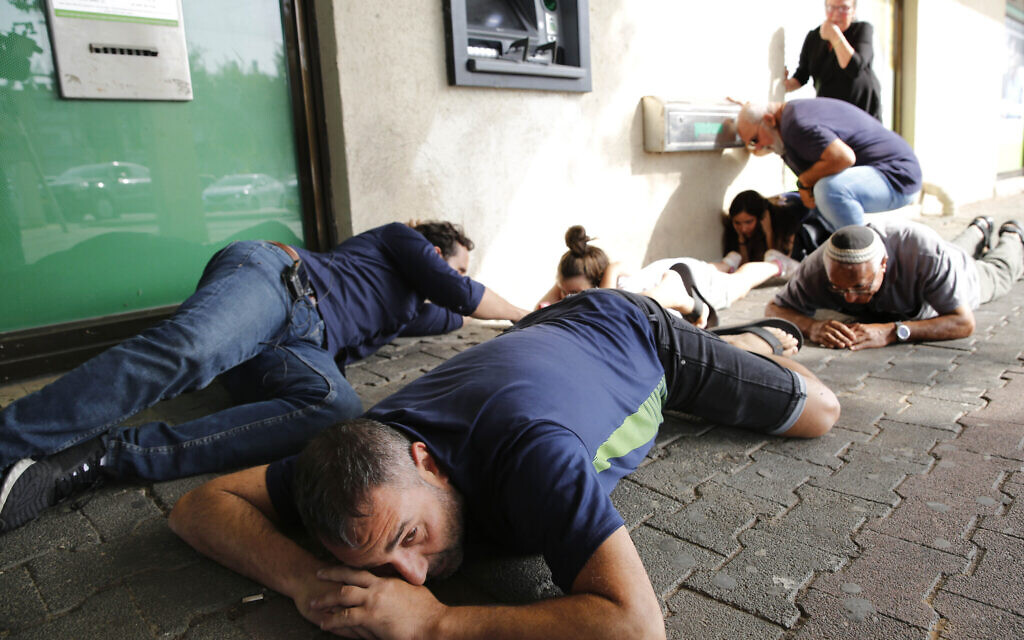 Israelis take cover while lying on the ground during a rocket attack from the neighbouring Palestinian Gaza Strip on November 13, 2019 in Ashkelon in southern Israel.  (Photo by GIL COHEN-MAGEN/AFP via Getty Images)