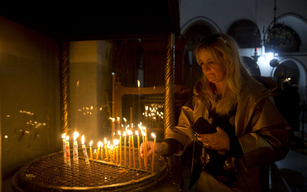 A visitor lights a candle at the Church of the Nativity built on top of the site where Christians believe Jesus Christ was born on Christmas Eve, in the West Bank City of Bethlehem, Tuesday, Dec. 24, 2019. (AP Photo/Majdi Mohammed)