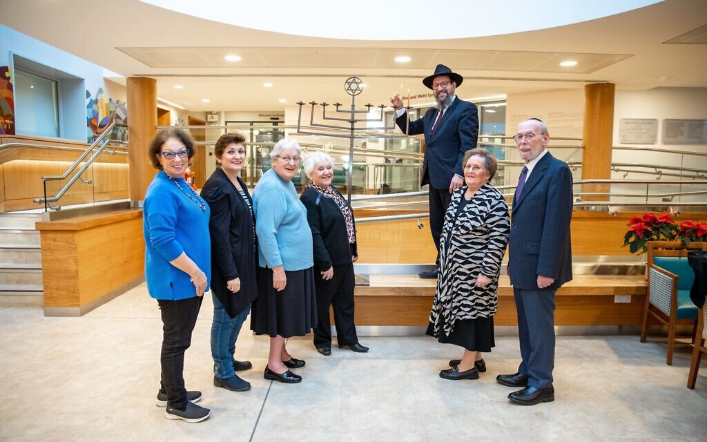 Left to right: Stephanie Lewis, Judith Goodman,  Jeanette, Linda, Mel Zeffert and his spouse, Rabbi Menachem Junik with the new menorah at Jewish Care’s Betty and Asher Loftus Centre (Credit: Jewish Care)