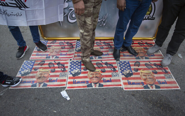 Mourners step over a U.S. flags with pictures of President Trump while waiting for the funeral of Iran's top general Qassem Soleimani and Abu Mahdi al-Muhandis, deputy commander of Iran-backed militias in Iraq known as the Popular Mobilization Forces, in Baghdad, Iraq, Saturday, Jan. 4, 2020. (AP Photo/Nasser Nasser)