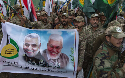 Iraqi militiamen march and chant anti U.S. slogans while carrying a picture of Soleimani