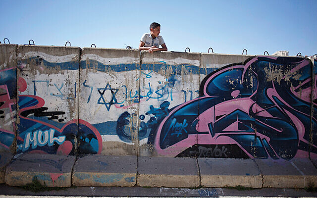 A Palestinian boy looks behind a wall separating Jewish part and Palestinian part of the West Bank. (AP Photo/Ariel Schalit)