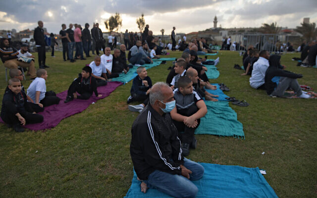 Muslim worshippers some wearing protective face masks gather for Eid al-Fitr prayers marking the end of the holy fasting month of Ramadan at a park in the mixed Arab Jewish city of Jaffa, near Tel Aviv, Israel, Sunday, May 24, 2020. (AP Photo/Oded Balilty)