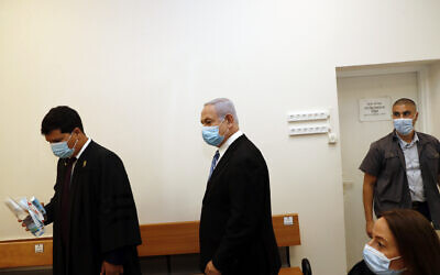 Israeli Prime Minister Benjamin Netanyahu, center, wearing a face mask in line with public health restrictions due to the coronavirus pandemic, enters the court room with his lawyer as his corruption trial opens at the Jerusalem District Court, Sunday, May 24, 2020.  He is the countryÕs first sitting prime minister ever to go on trial, facing charges of fraud, breach of trust, and accepting bribes in a series of corruption cases stemming from ties to wealthy friends. (Ronen Zvulun/ Pool Photo via AP)