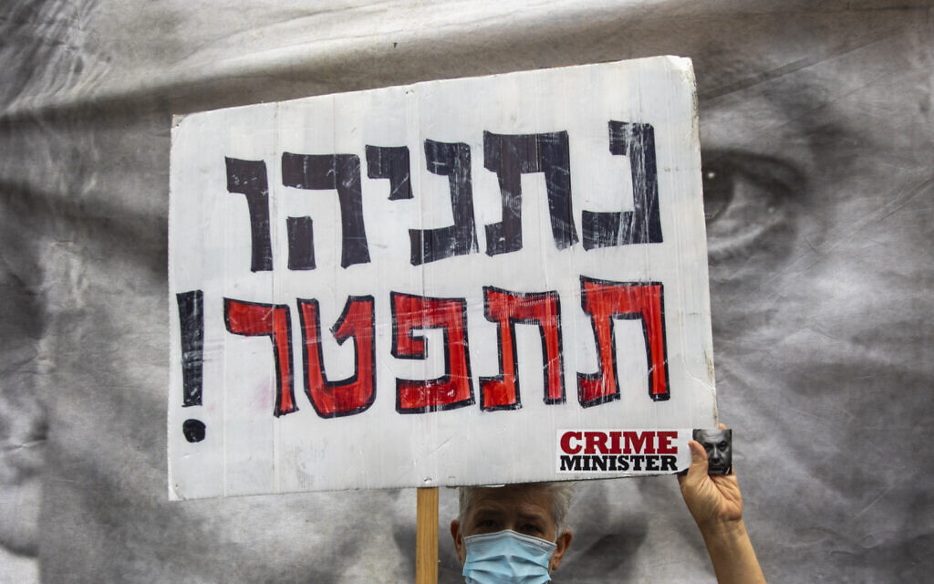 A protester against Israel's Prime Minister Benjamin Netanyahu holds a placard that reads, "Netanyahu resign," during a protest outside his residence in Jerusalem, Sunday, May 24, 2020. (AP Photo/Ariel Schalit) A protester against Israel's Prime Minister Benjamin Netanyahu holds a placard that reads, "Netanyahu resign," during a protest outside his residence in Jerusalem, Sunday, May 24, 2020. (AP Photo/Ariel Schalit)