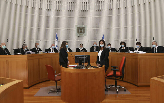 A panel of 11 Israeli Supreme Court judges wearing face masks hear arguments against the legality of Prime Minister Benjamin NetanyahuÕs coalition deal with his former rival, Benny Gantz, at the Israeli Supreme Court in Jerusalem, Monday, May 4, 2020. (Abir Sultan/Pool via AP)