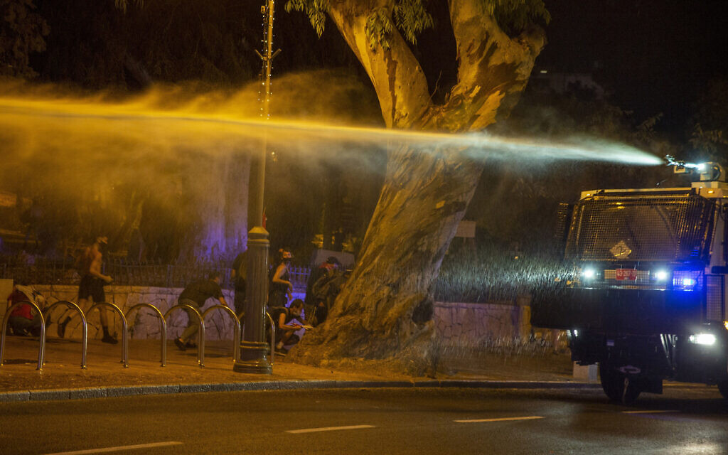 Police use a water cannon to disperse demonstrators during a protest against Israel's Prime Minister Benjamin Netanyahu outside his residence in Jerusalem, early Friday, July 24, 2020. Protesters demanded that the embattled leader resign as he faces a trial on corruption charges and grapples with a deepening coronavirus crisis. (AP Photo/Ariel Schalit)