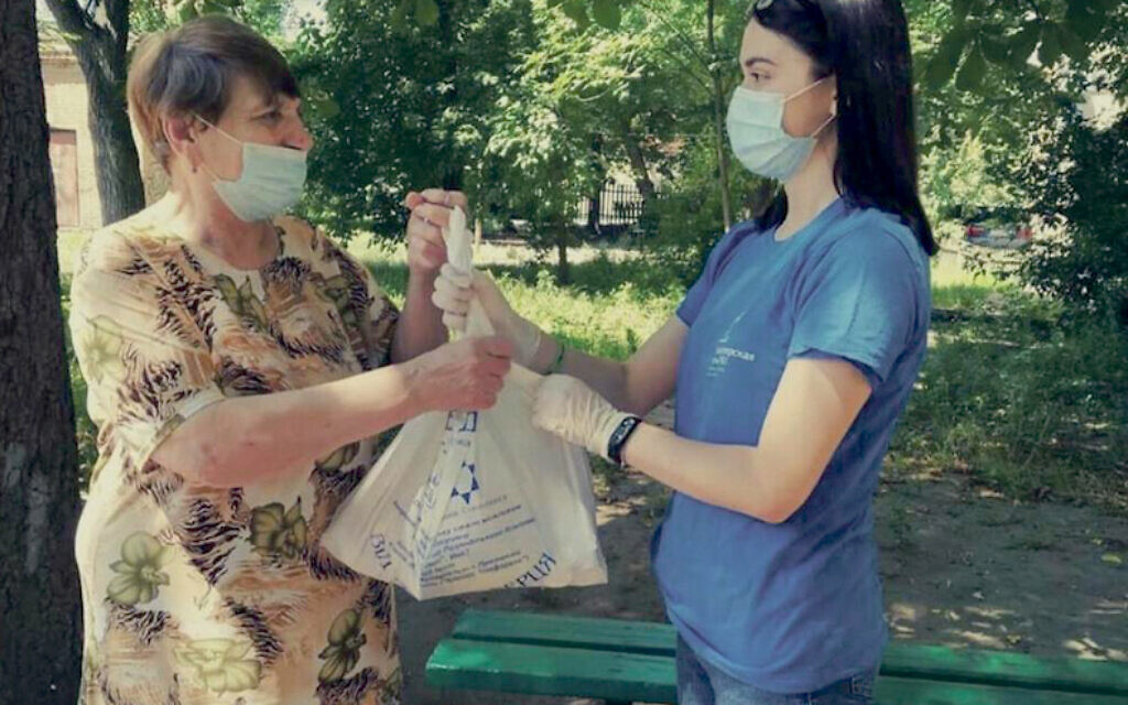 A JDC employee, right, delivers an aid package to a Jewish woman