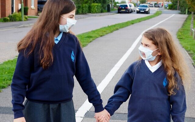 Sisters on their way to school with transparent face-masks
